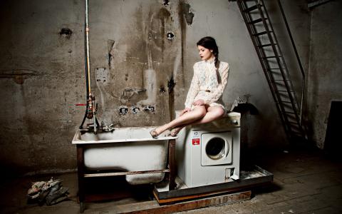 女人坐在一台洗衣机